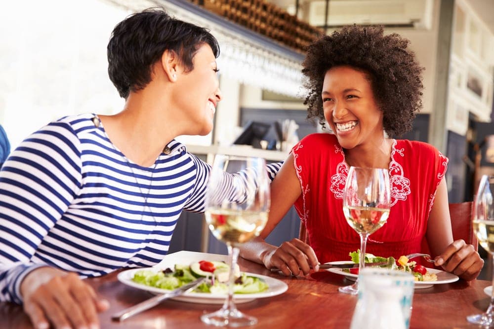 Two women enjoying a meal and laughing together at a restaurant.