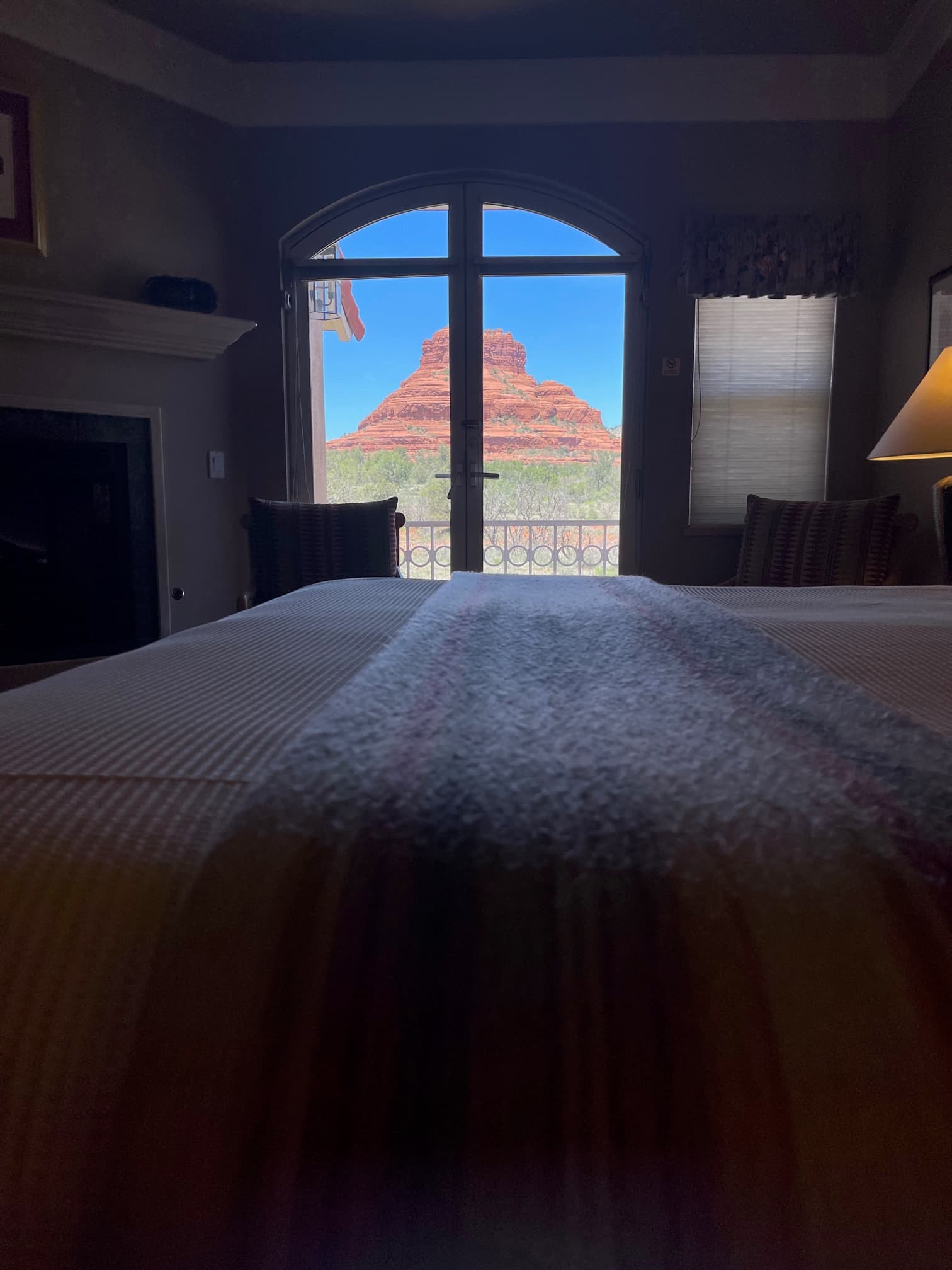 A view of a red rock formation through a large window from a cozy bedroom.