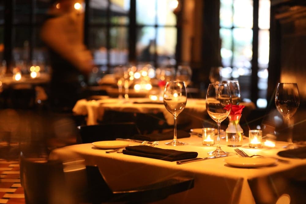 A softly lit restaurant with elegantly set tables and wine glasses.