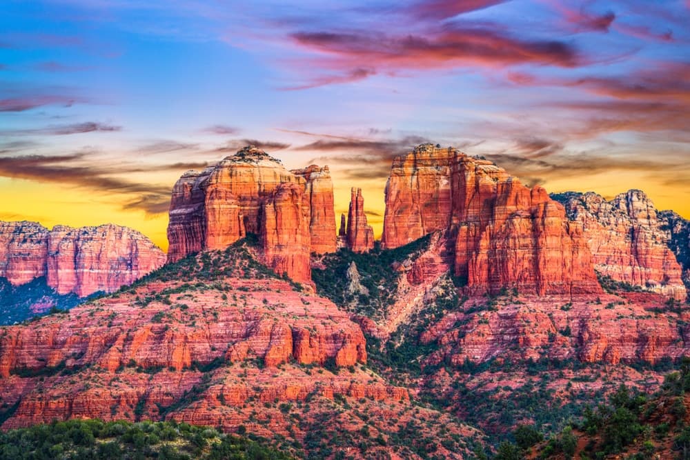 Vibrant red rock formations silhouetted against a colorful sunset sky.
