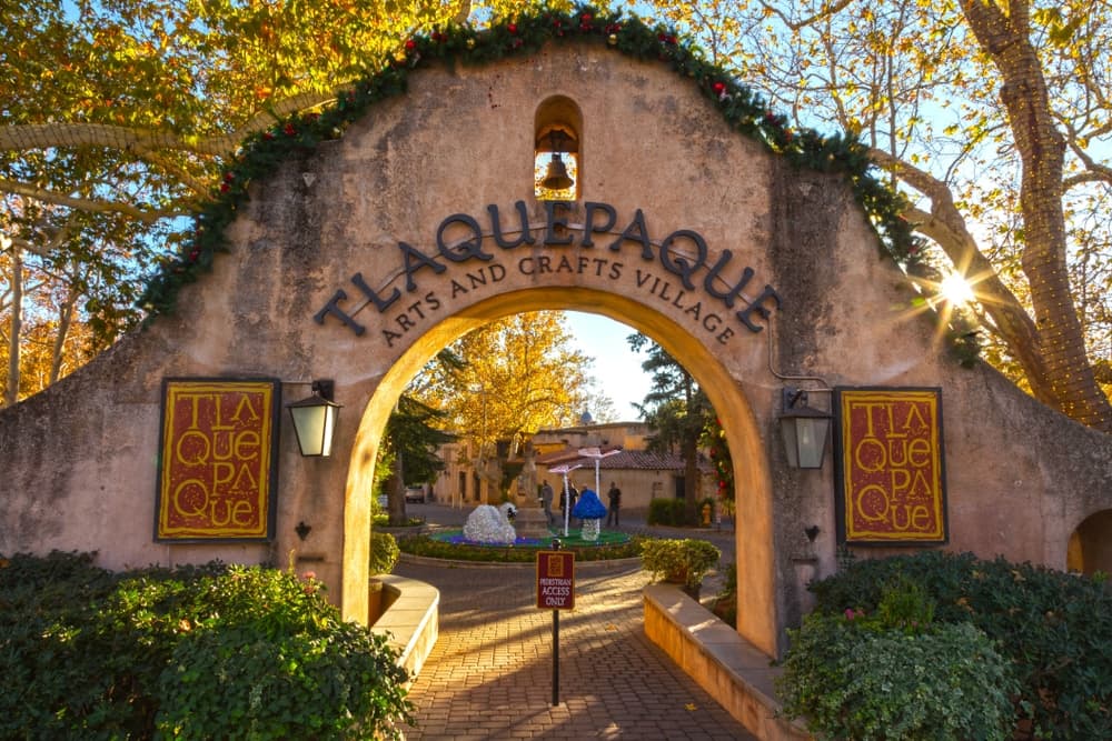 Archway entrance to Tlaquepaque Arts and Crafts Village surrounded by autumn foliage.