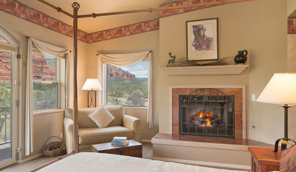 Cozy bedroom with a fireplace and scenic views through large windows.