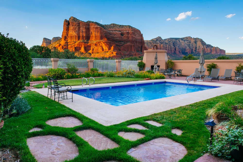 A serene backyard featuring a swimming pool with a view of majestic red rock formations in the background.