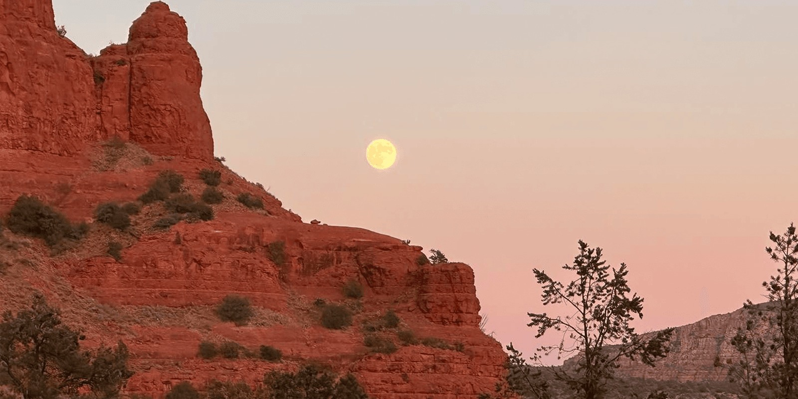 Golden moon at moon rise with view of Arizona red rocks in foreground