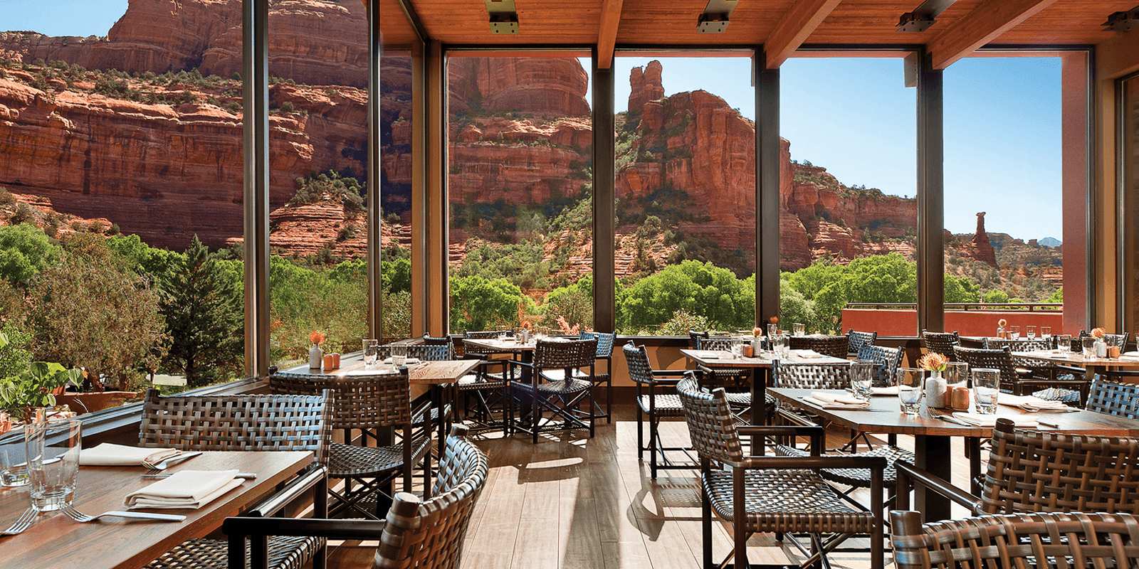 Modern dining area with wooden furnishings and large windows overlooking red rock formations.