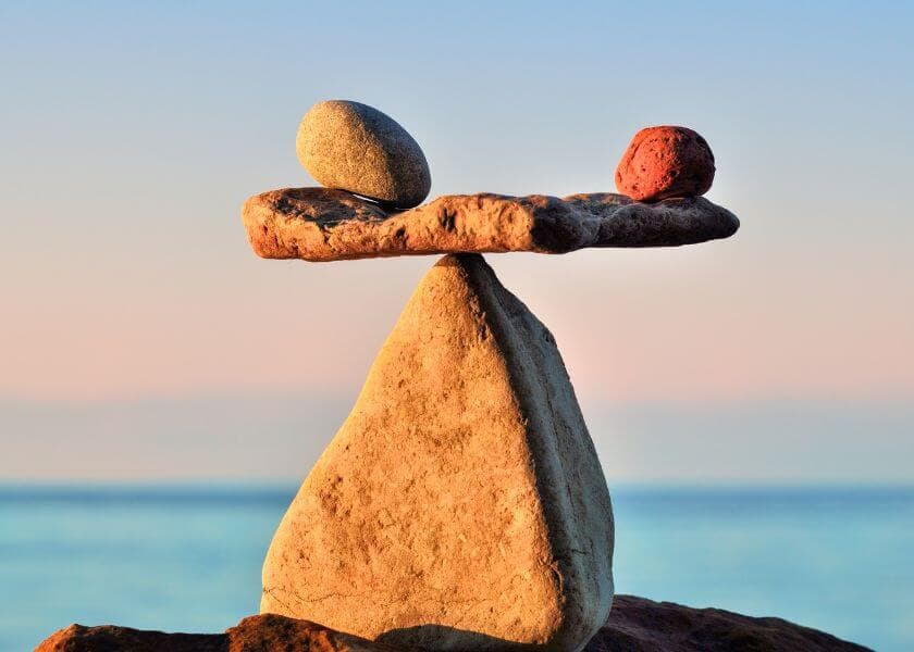 A balanced arrangement of stones with a flat stone supporting two smaller stones on top against a serene background. A balanced arrangement of stones with a flat stone supporting two smaller stones on top against a serene background.