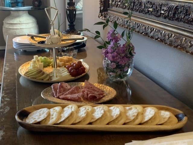 Assorted cheeses, meats, fruits, and cookies arranged on a wooden table with decorative plates.