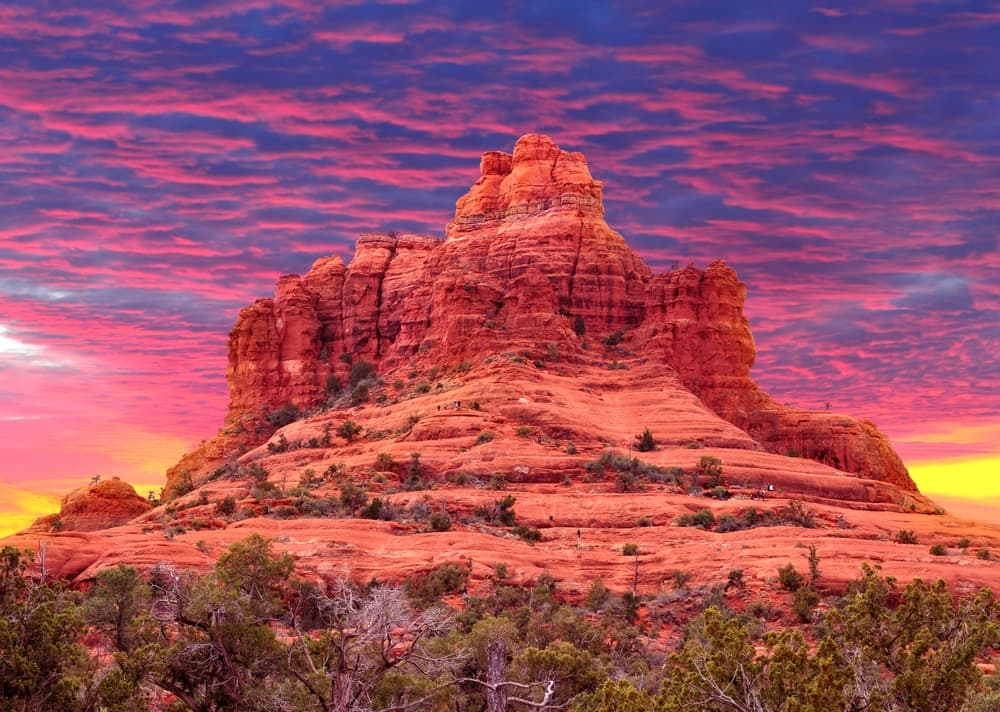 A striking red rock formation under a colorful sunset sky.