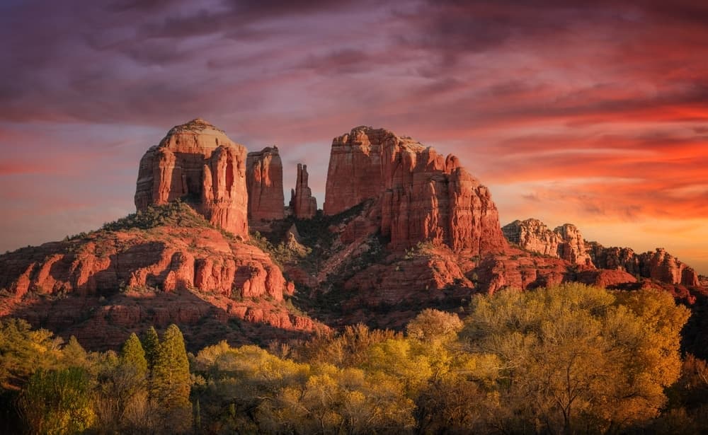 A vibrant sunset over red rock formations surrounded by autumn foliage. A vibrant sunset over red rock formations surrounded by autumn foliage.