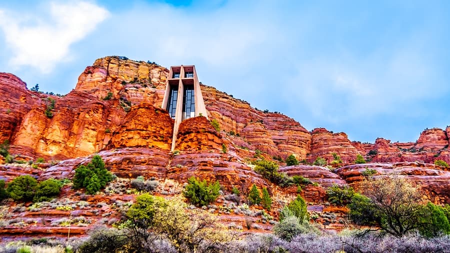 A modern structure perched on vibrant red rock formations under a blue sky.