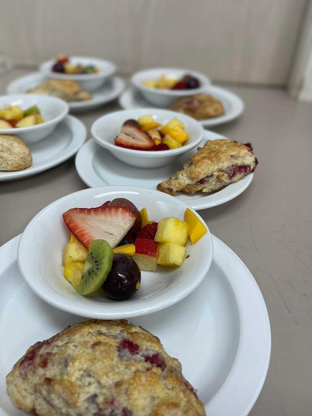 A plate with scones and small bowls of mixed fruit.
